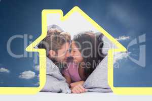 Composite image of beautiful couple wrapped in the duvet