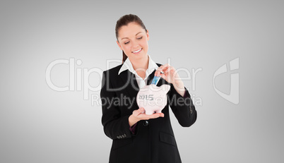 Composite image of beautiful woman in suit inserting a money bil
