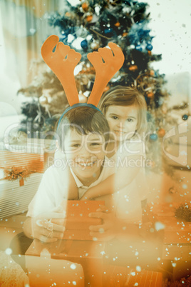 Composite image of happy brother and sister celebrating christma