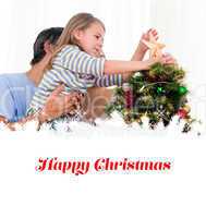 Composite image of little girl placing a star in a christmas tre