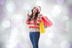 Composite image of happy brunette holding shopping bags and cred