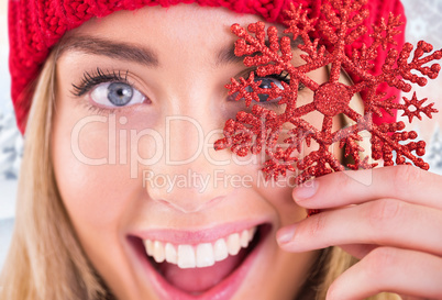 Composite image of happy blonde holding red snowflake