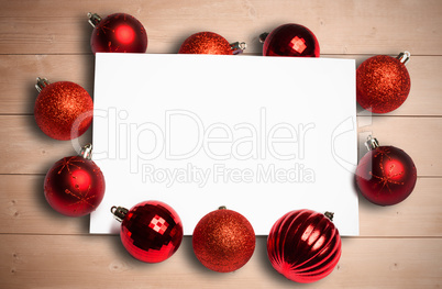 Composite image of red christmas baubles surrounding white page