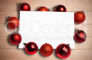 Composite image of red christmas baubles surrounding white page