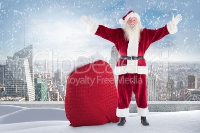 Composite image of santa standing on snowy ledge