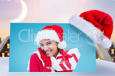 Composite image of festive brunette holding gift