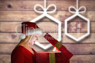 Composite image of festive blonde opening a gift