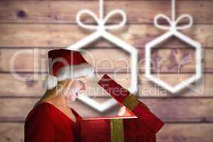 Composite image of festive blonde opening a gift