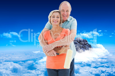 Composite image of happy older couple holding paint roller