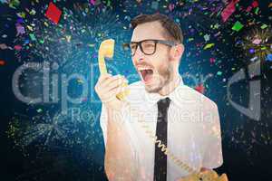 Composite image of geeky businessman shouting at telephone