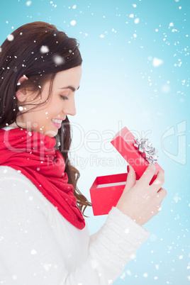 Composite image of smiling brunette opening christmas present