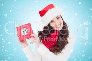 Composite image of joyful brunette presenting christmas gift