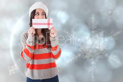 Composite image of festive brunette holding a gift