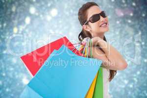 Composite image of brunette posing and holding shopping bags