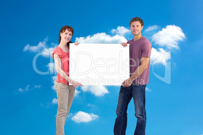 Composite image of couple holding a white sign