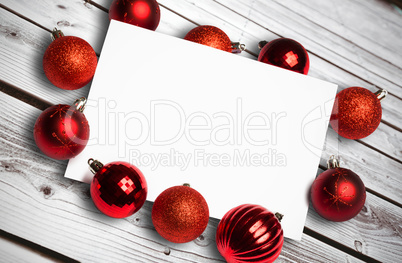 Composite image of red christmas baubles surrounding white page