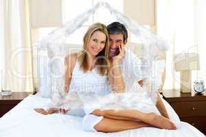 Composite image of portrait of lovers sitting on bed