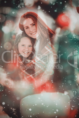 Composite image of festive mother and daughter wrapped in blanke