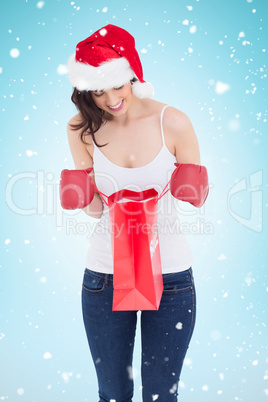 Composite image of happy brunette in boxing gloves looking in sh
