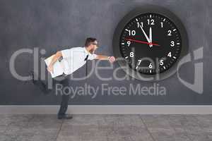 Composite image of geeky young businessman running late