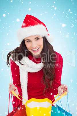 Composite image of festive brunette opening shopping bag