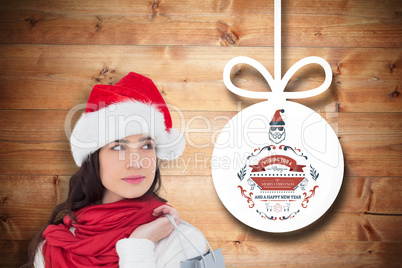 Composite image of brunette in santa hat holding shopping bag