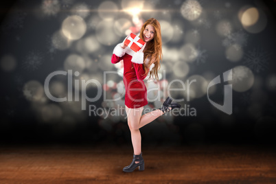 Composite image of festive redhead holding a gift