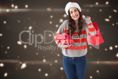 Composite image of smiling brunette holding gifts and showing sh