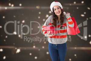 Composite image of smiling brunette holding gifts and showing sh