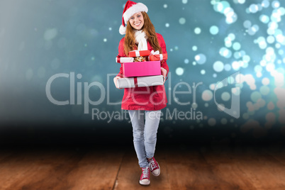 Composite image of festive redhead holding pile of gifts