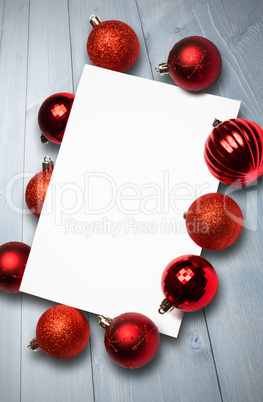 Composite image of red christmas baubles surrounding white page