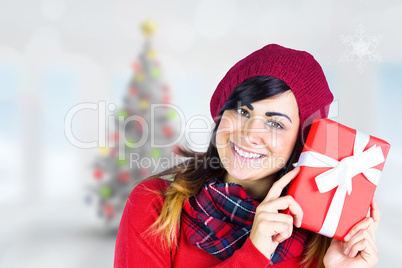 Composite image of smiling brunette in red hat holding gift