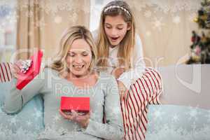 Composite image of mother opening christmas gift with daughter