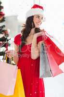 Composite image of brunette in red dress holding shopping bags