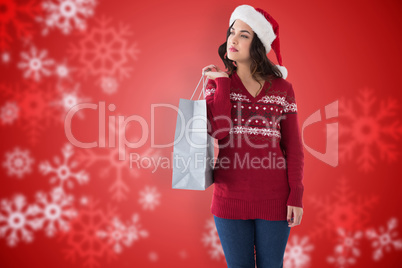 Composite image of thoughful brunette in santa hat holding shopp