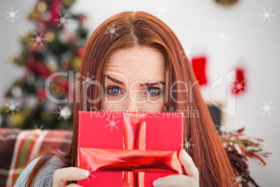 Composite image of festive redhead with gift on the couch