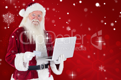 Composite image of santa pays with credit card on a laptop