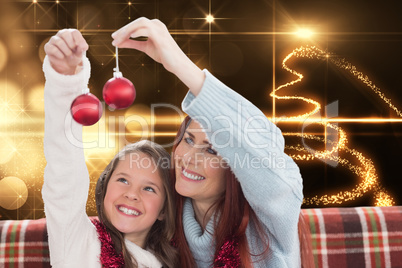 Composite image of mother and daughter holding baubles