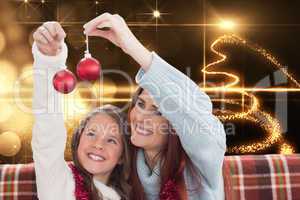 Composite image of mother and daughter holding baubles