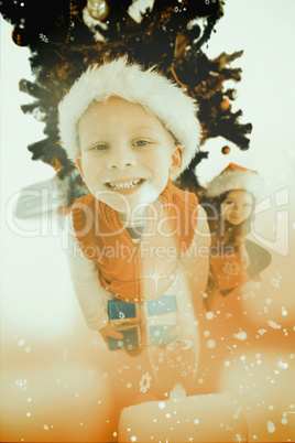 Composite image of festive little siblings smiling at camera hol Composite image of festive little siblings smiling at camera hol