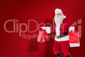 Composite image of smiling santa claus holding shopping bags