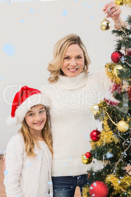 Composite image of festive mother and daughter decorating christmas tree