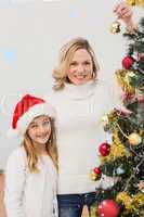 Composite image of festive mother and daughter decorating christmas tree