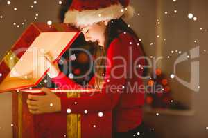 Composite image of festive little girl opening a glowing christm