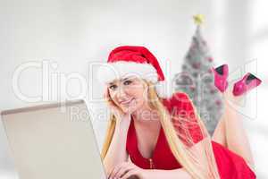 Composite image of festive blonde using a laptop
