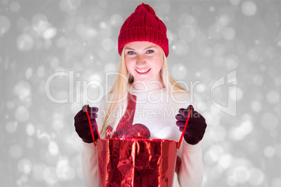 Composite image of festive blonde opening a gift bag