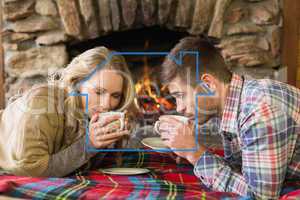 Composite image of romantic couple drinking tea in front of lit