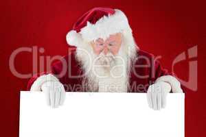 Composite image of santa holds a sign and looks down