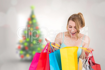 Composite image of excited woman looking at many shopping bags