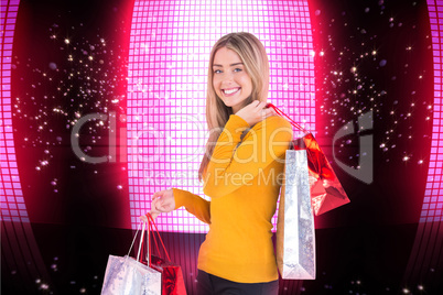 Composite image of stylish blonde smiling with shopping bags